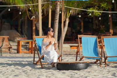 Young woman sitting on chair at beach