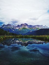 Scenic view of lake and mountains against cloudy sky