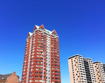 Low angle view of modern office building against blue sky