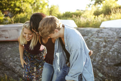 Cheerful young friends standing on rock at harbor