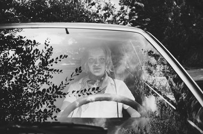 Portrait of woman in car seen through windshield