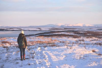 Rear view of woman standing on snow covered land