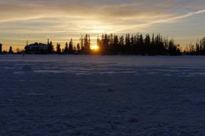 Winter landscape against sky during sunset