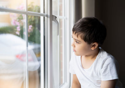 Side view of boy looking through window