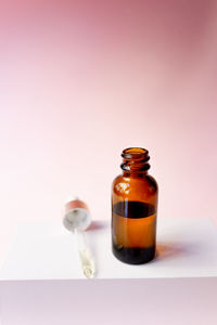 Essential oil serum glass pipette and bottle on pink background