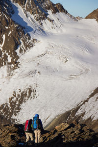 Rear view of people standing on snowcapped mountain