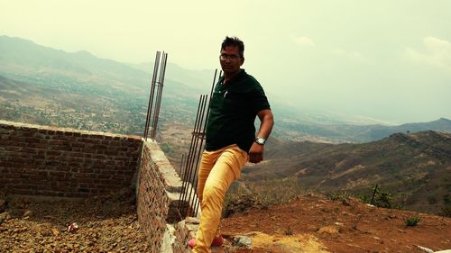 Young man looking at mountains against sky