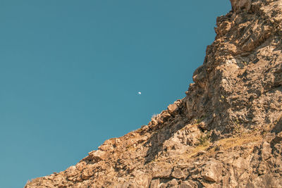 Low angle view of rocky mountains against clear blue sky