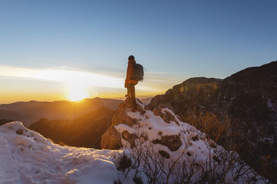 Hiker standing on rock at sunset