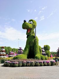 Statue amidst plants in park against sky