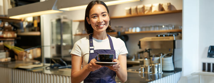 Portrait of young woman using mobile phone in cafe