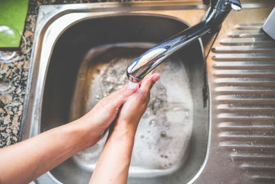 Cropped image of person washing hand in sink