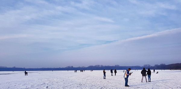 People on snow covered landscape against sky