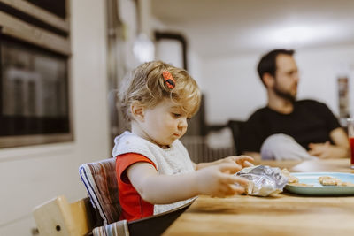 Close-up of cute girl eating crackers on table at home