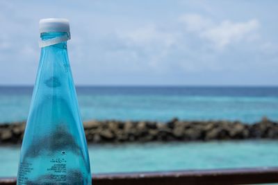 Close-up of bottle against blue sea