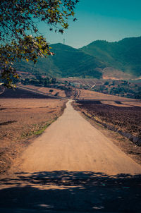 Road leading towards mountains against sky