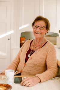 Portrait of smiling retired senior woman sitting at table in nursing home