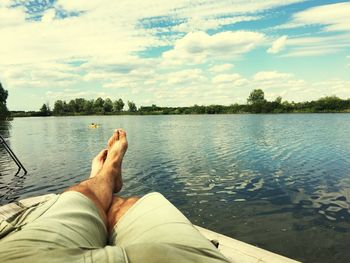 Low section of man relaxing on lake