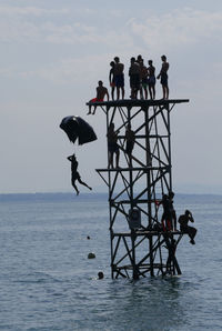 People on built structure in sea against sky