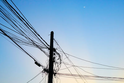 Low angle view of electricity pylon against clear blue sky