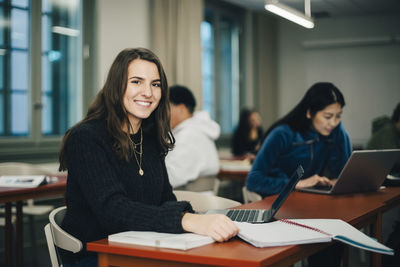 Portrait of a smiling young woman sitting on table