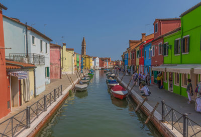 Boats moored in canal amidst buildings against sky