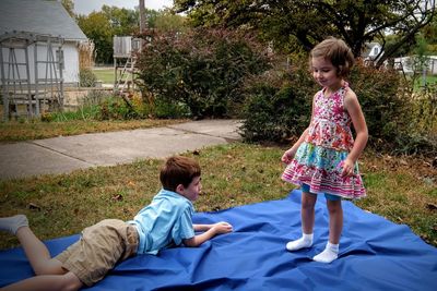 Siblings on blue sheet in yard
