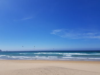 Scenic view of beach against blue sky