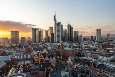 Aerial view of buildings in city against sky during sunset