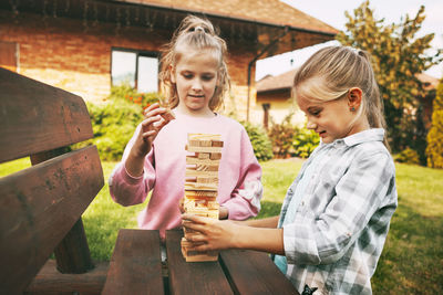 Cute girls playing with block shapes on bench at yard
