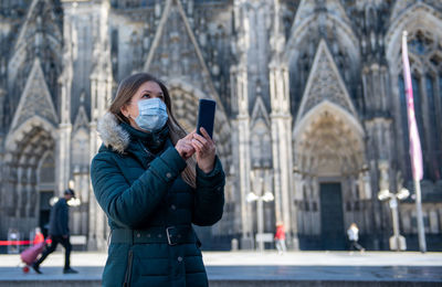 Young woman using smart phone in city during winter