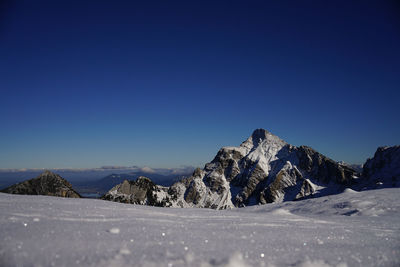Scenic view of snowcapped mountains against clear blue sky
