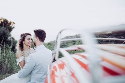 Happy couple kissing against sky