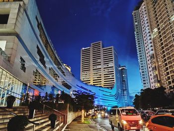 Street amidst buildings against blue sky in city