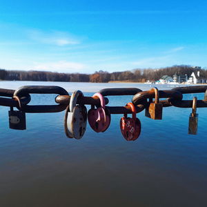 Close-up of padlocks on railing against blue sky