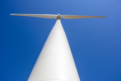 Wind turbine against blue sky from low angle