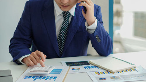 Midsection of man using mobile phone on table