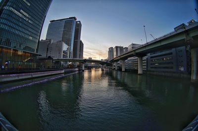 Bridge over river by buildings against sky in city