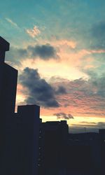 Silhouette of building against cloudy sky at sunset