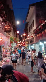 People walking on illuminated street at night