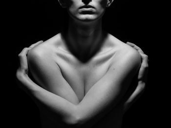 Midsection of young woman standing against black background