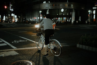 Rear view of man riding bicycle on city street