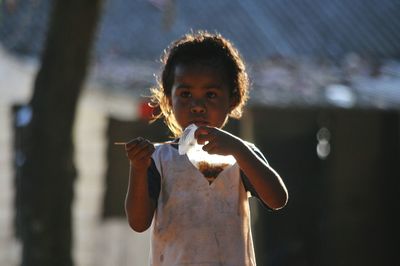 Girl eating food while standing outdoors