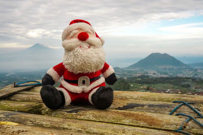 Stuffed toy on field against mountain
