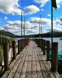 Wooden pier leading towards sea against sky