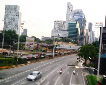 View of city street and modern buildings against sky