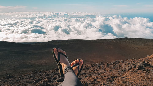 Low section of woman relaxing against sky