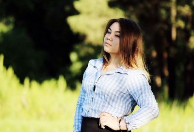 Young woman looking away while standing on field