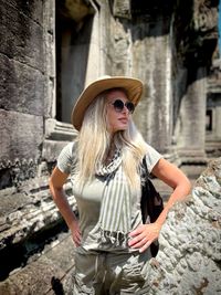 Portrait of young woman standing against rock