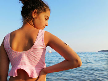 Girl is standing on the seashore. on right arm is white sensor for continuous glucose monitoring cgm